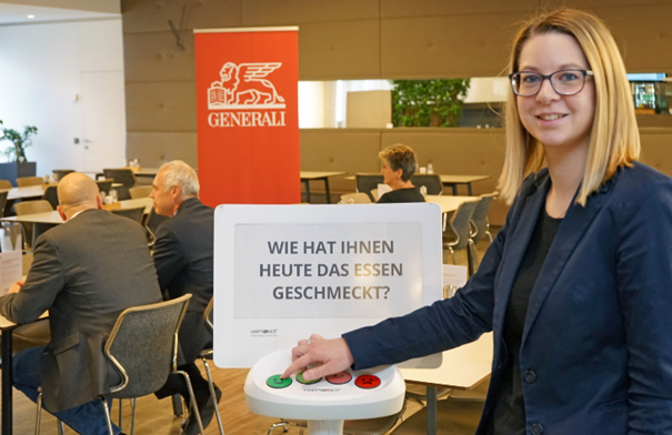 Eine Mitarbeiterin gibt ihre Zufriedenheit mit dem Betriebsrestaurant über ein Smiley Terminal bekannt.