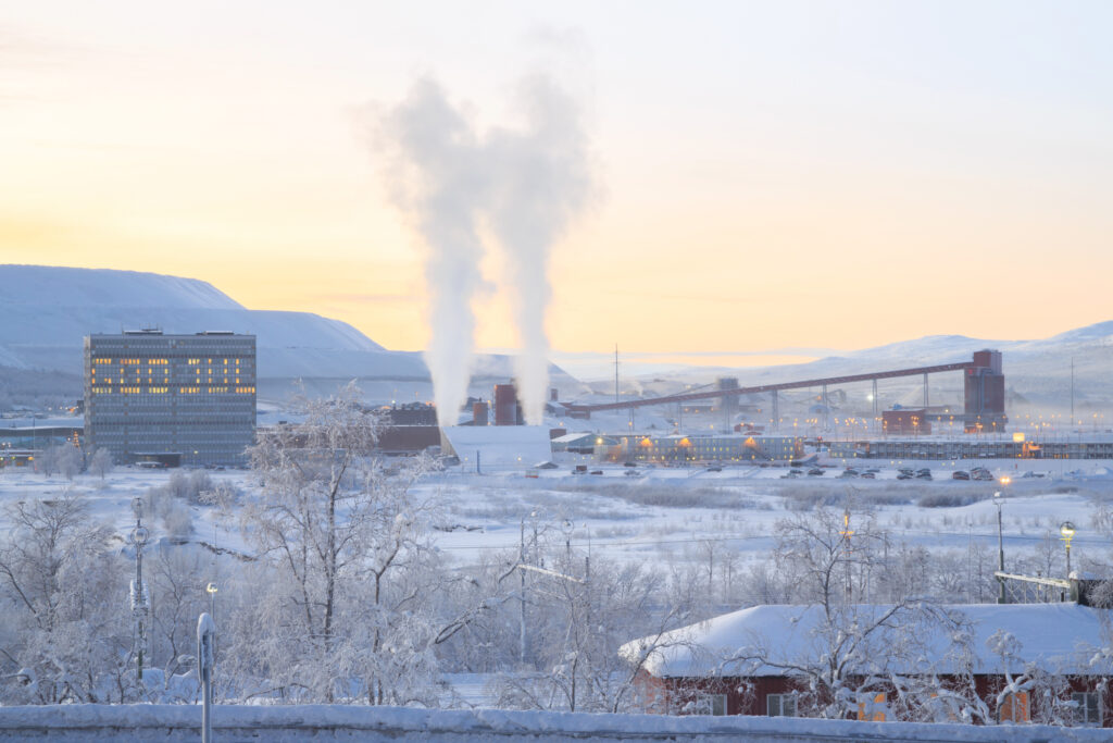 Das Foto zeigt eine typische Landschaft in Skandinavien. Es ist Winter und man sieht eine schwedischsprachige Aufschrift auf einem Farbrikgebäude in Schweden.