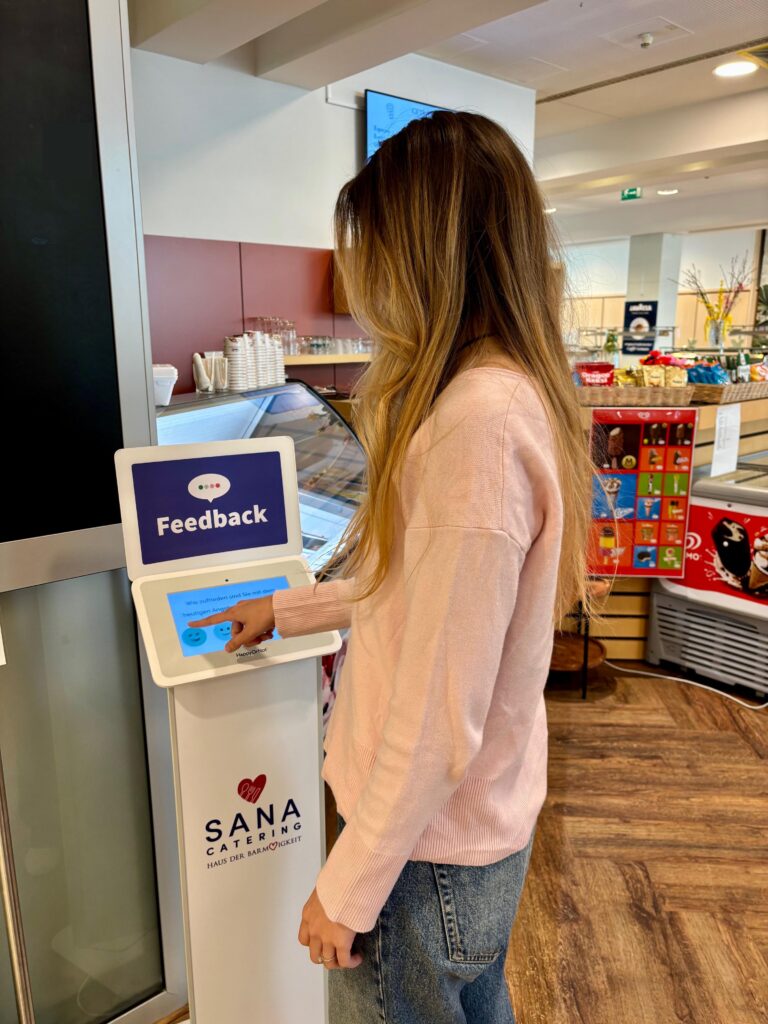 Ein Gast hinterlässt eine Bewertung auf dem Smiley Touch Terminal.